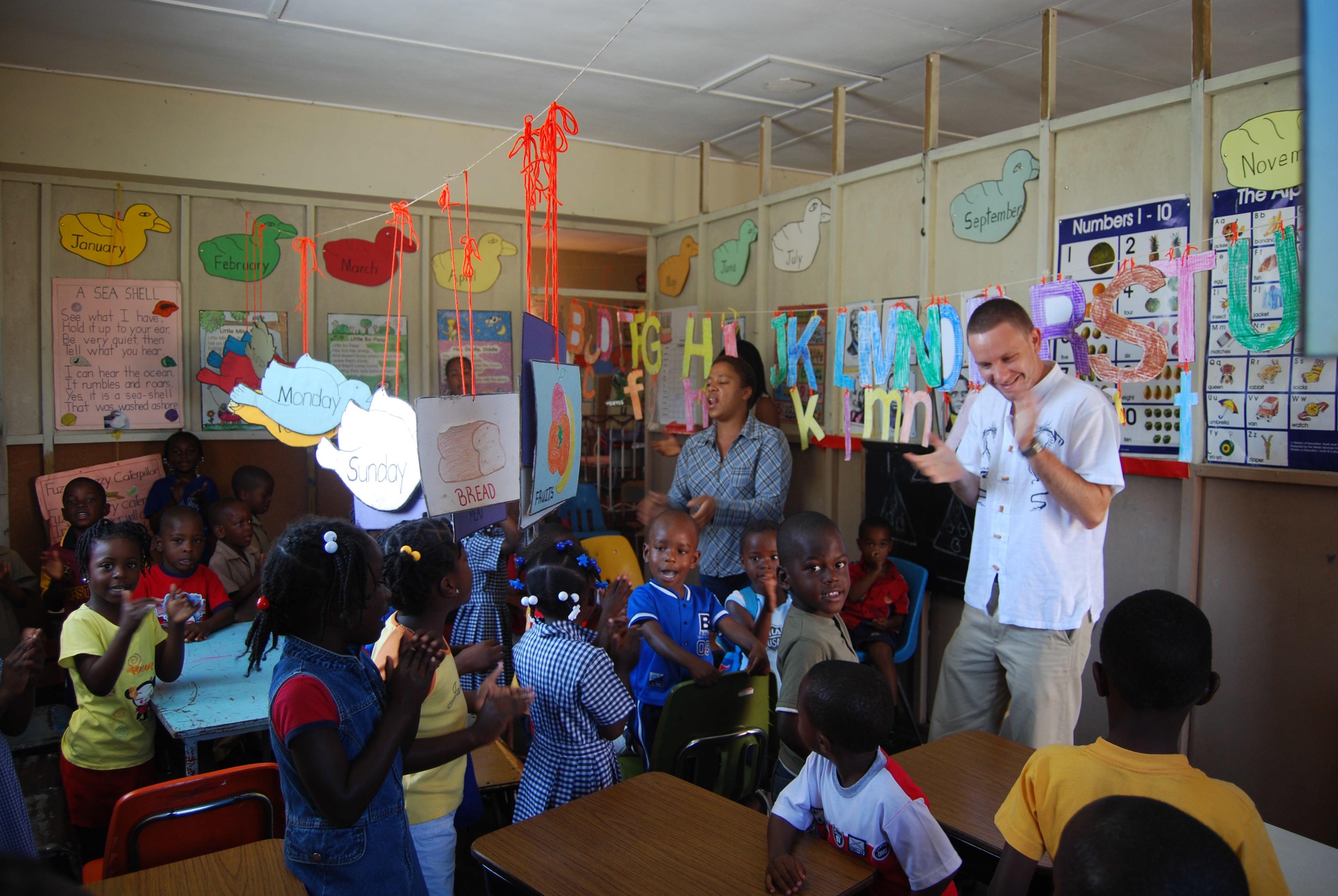 Projects Abroad volunteer clapping along to an English song at a volunteer teaching placement in Jamaica Teaching volunteers in Jamaica sing and dance to an English song with their students
